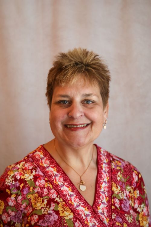 A white woman with short hair and a red shirt.