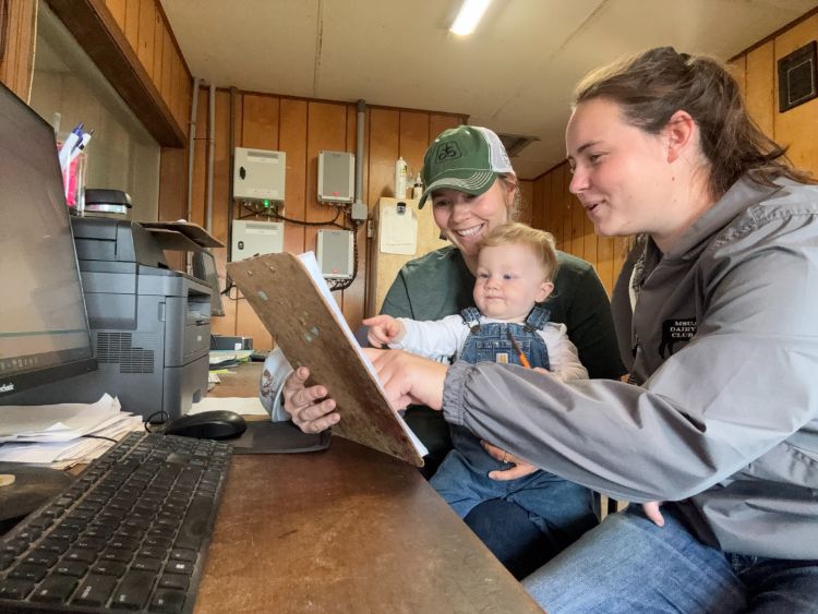 two people and a baby looking at a computer screen