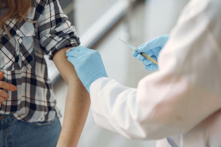 A medical professional administering a vaccine to someone.