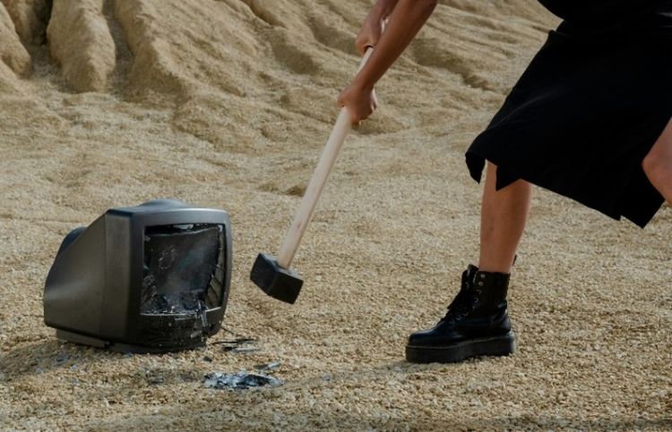A person hitting a television with a mallet.