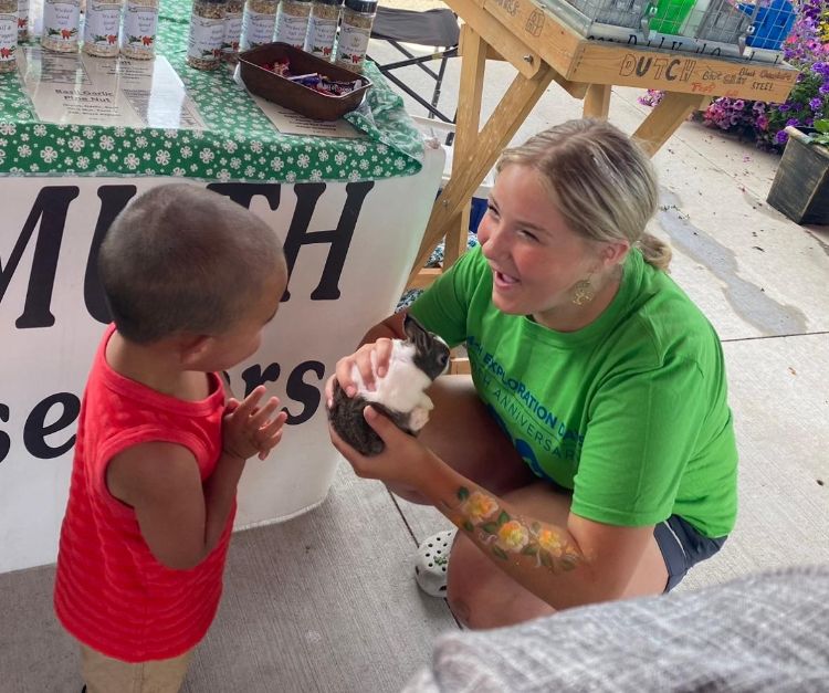 Elliana Specht holding an animal and showing a young child.