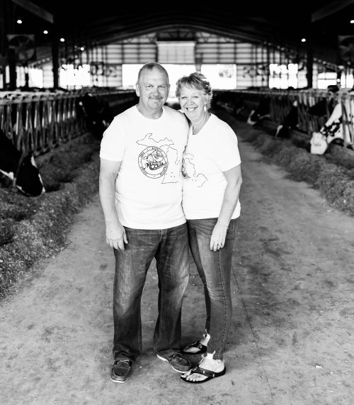 Two people standing in a cow barn