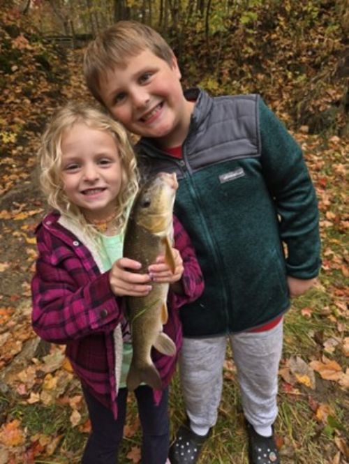Two young kids holding up a fish.