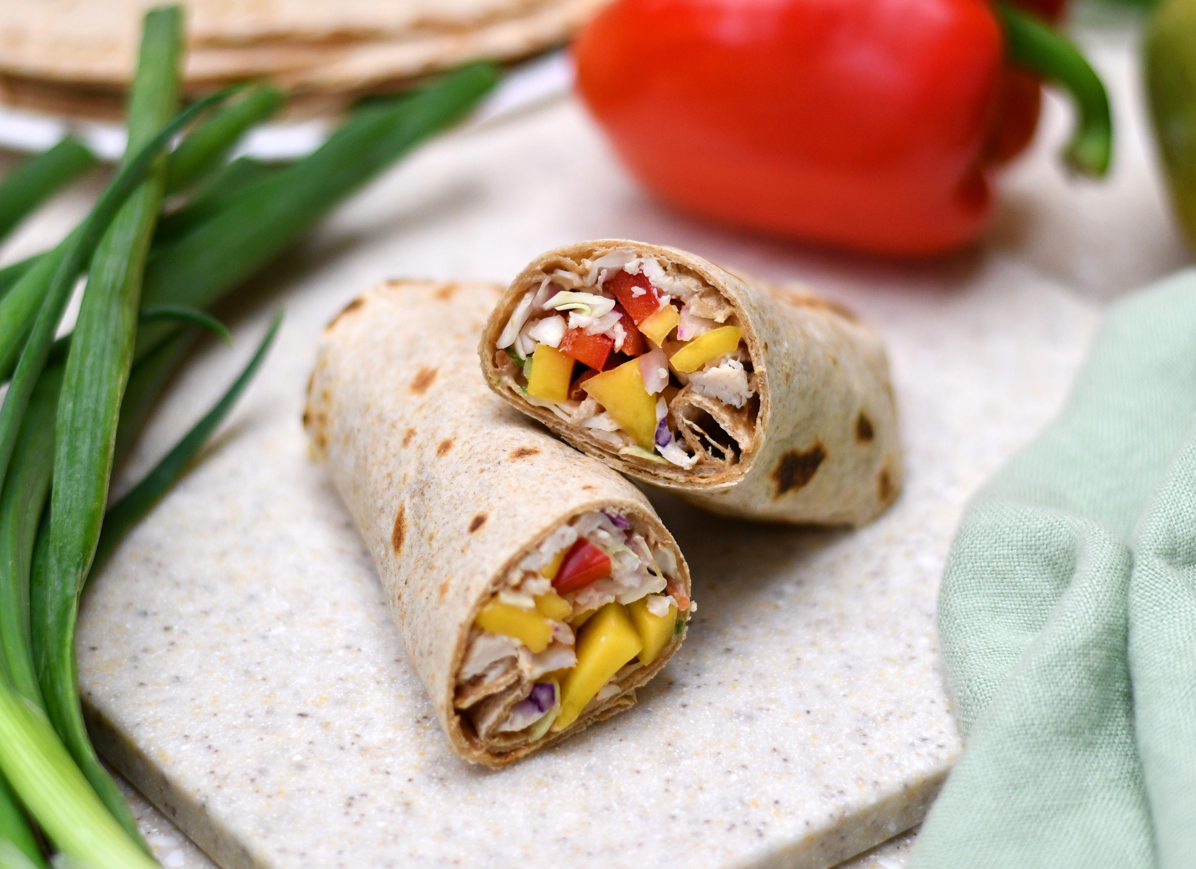 A photo of a wrap with chicken and mango