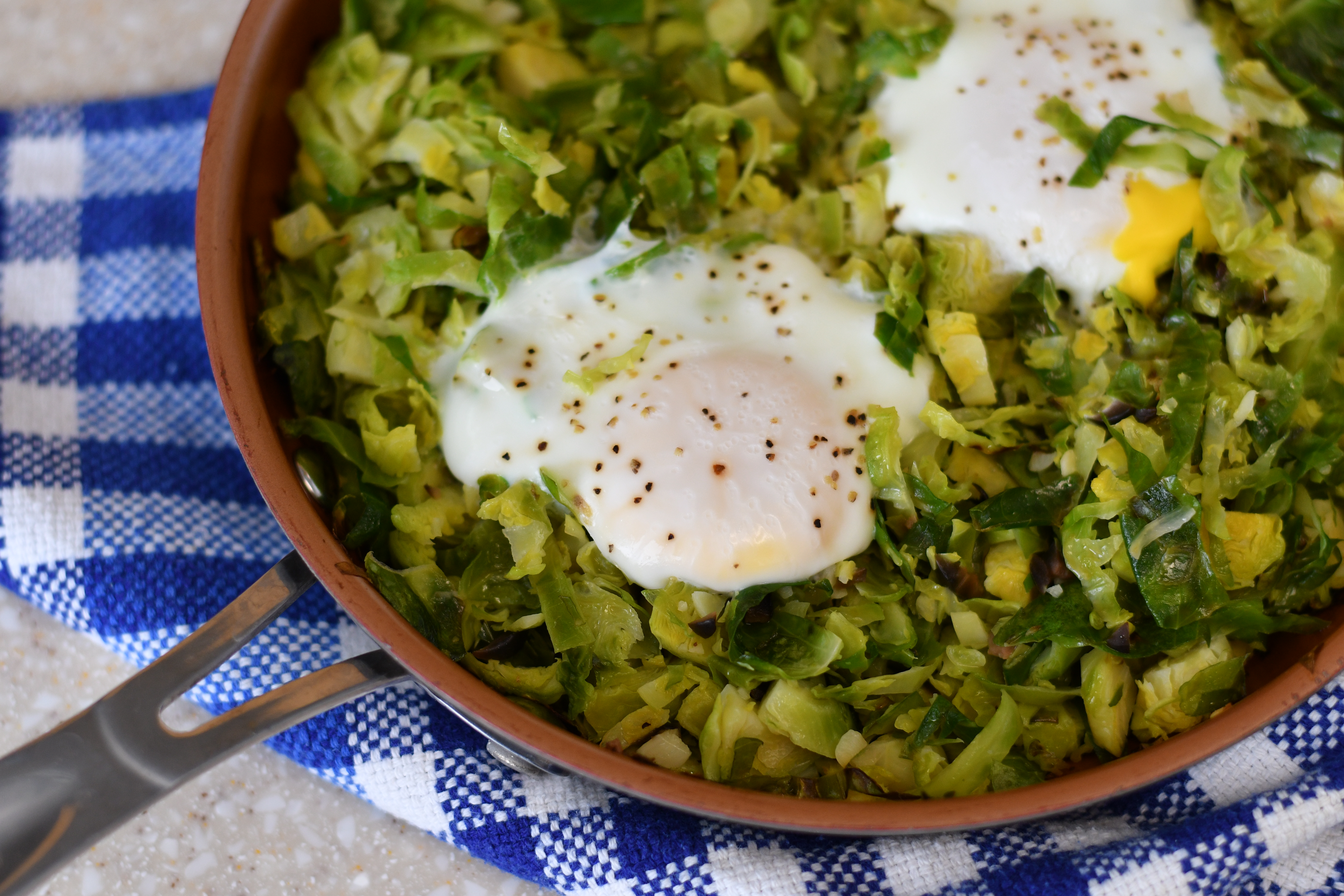 A photo of a pan of brussels sprouts topped with eggs