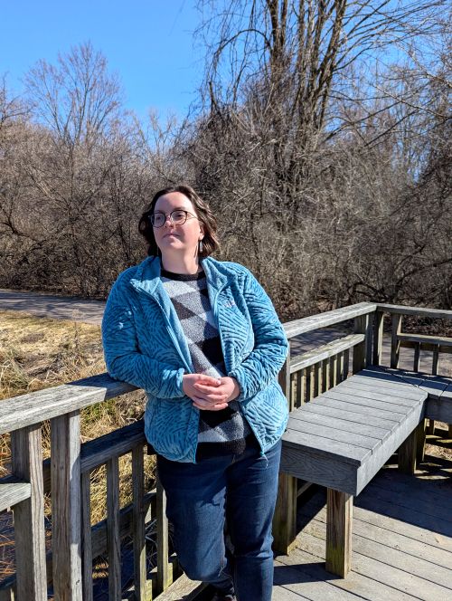 Forestry student Rachel Adams posing for a picture on a deck with a forest in the background.
