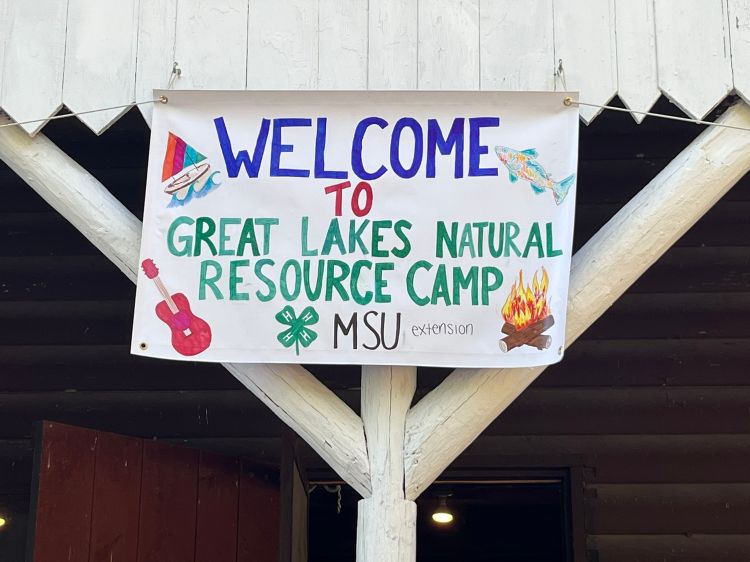 Banner hanging from a wooden overhang says 