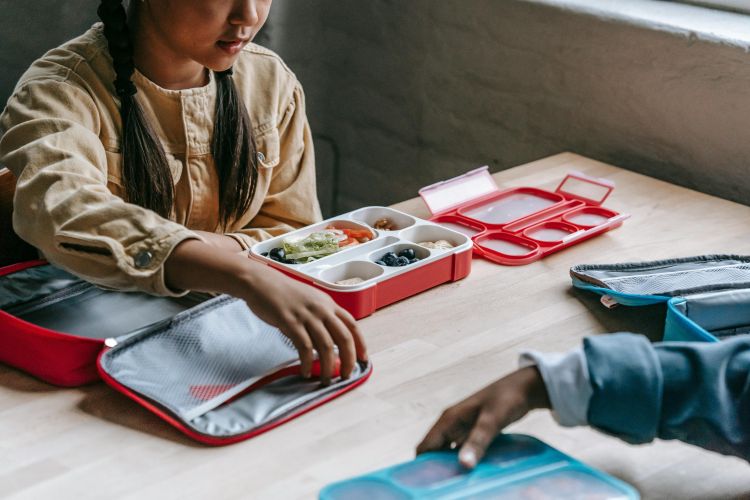 Photo of a child eating a school lunch with a diversity of nutritious foods.