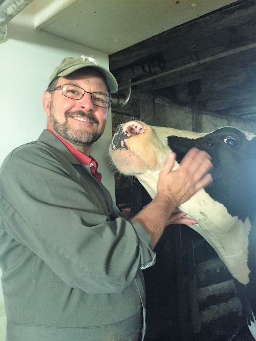 Photo of Extension Educator, Phil Durst, posing with a dairy cow.