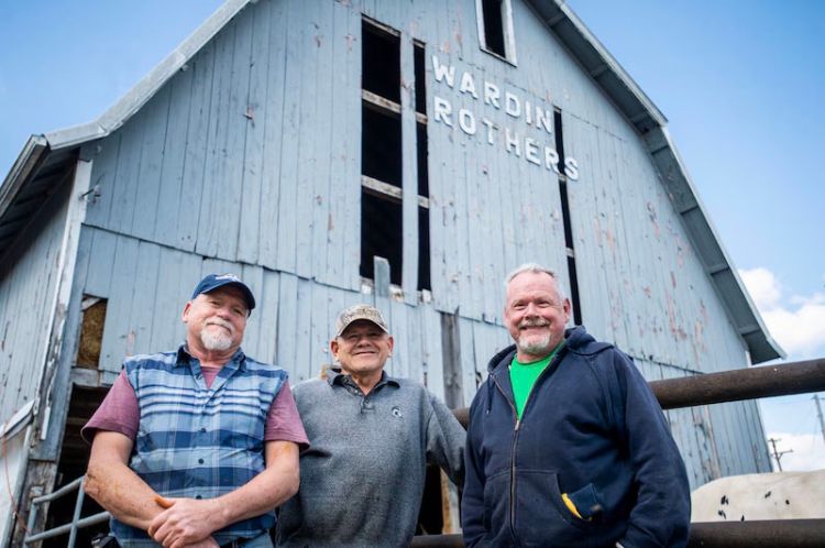 Photo of three men standing in front of a barn.
