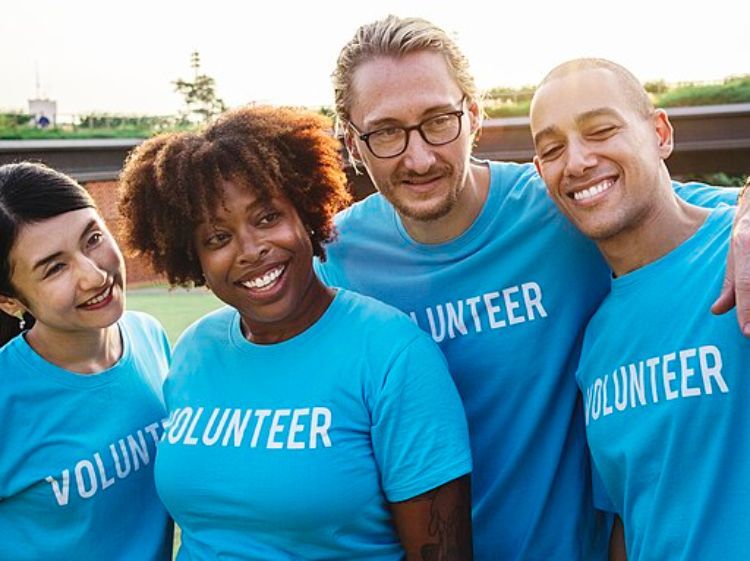 a group of diverse adults wearing blue tshirts that say volunteer.