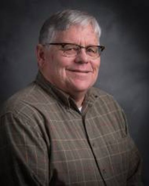 Paul Bloese poses for a headshot in front of a dark grey background