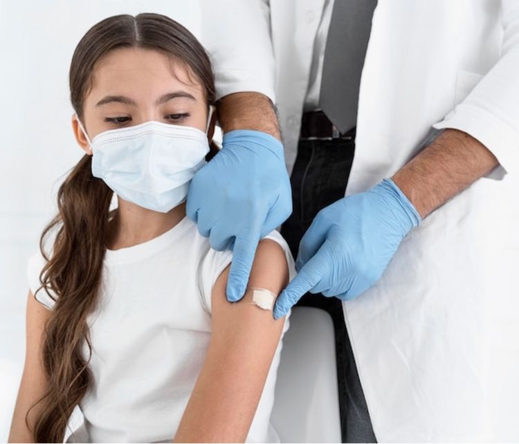 A doctor places a bandage on the arm of a patient after administering a vaccine.