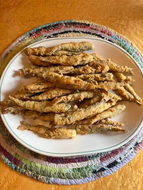 Fried smelt are shown on a dinner plate.