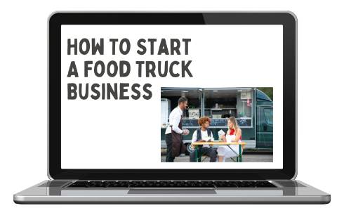 Food truck owner speaking with two customers sitting at picnic table in front of food truck.