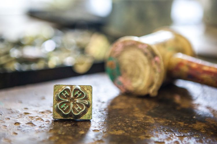 A distant gavel with a 4-H clover pin up close.