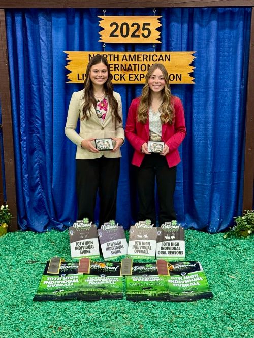 Two girls displaying their awards in front of a backdrop that says 2025 North American International Livestock Exposition.