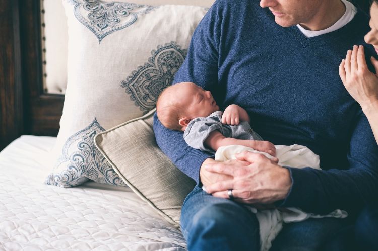 A man in a blue shirt holding a tiny baby.