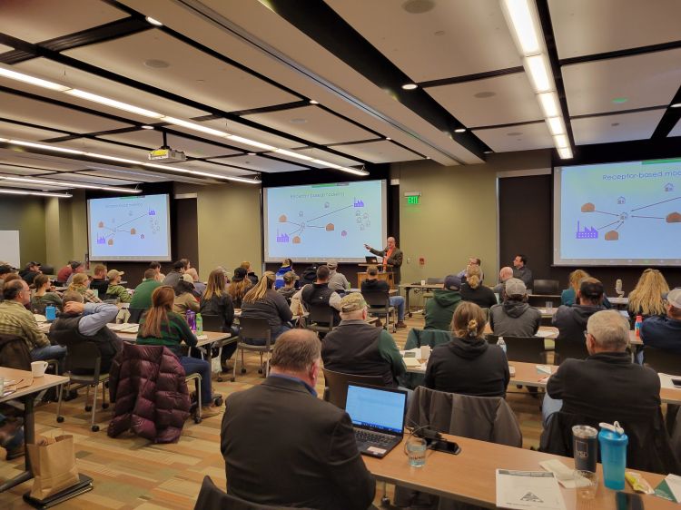 Participants of a past Michigan Manure Summit sit in a room watching a speaker give a presentation.