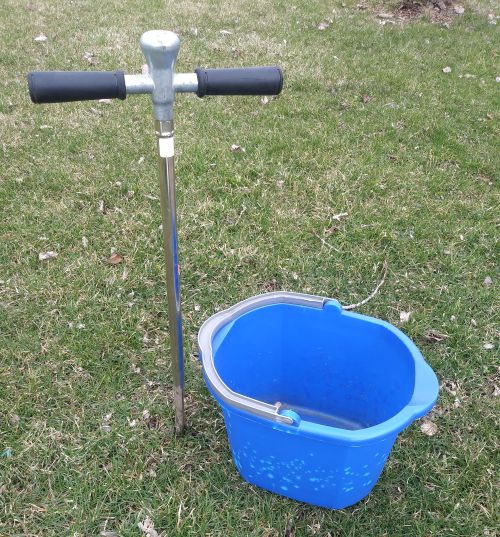A soil probe and a blue bucket.