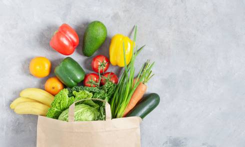 Photo of a grocery bag overflowing with vegetables.