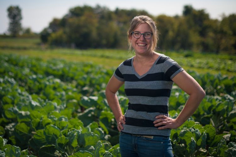 Woman in striped shirt standing in front of a green field of crops