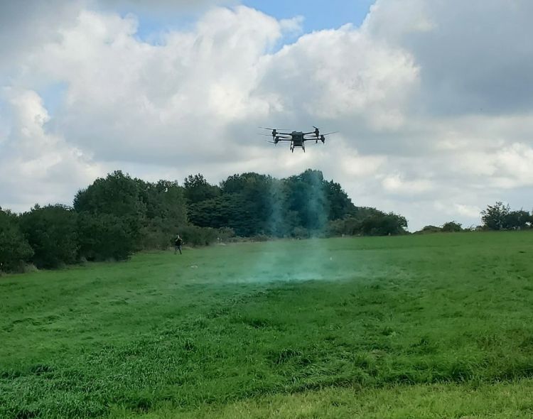 A drone coating a field with a blue substance.