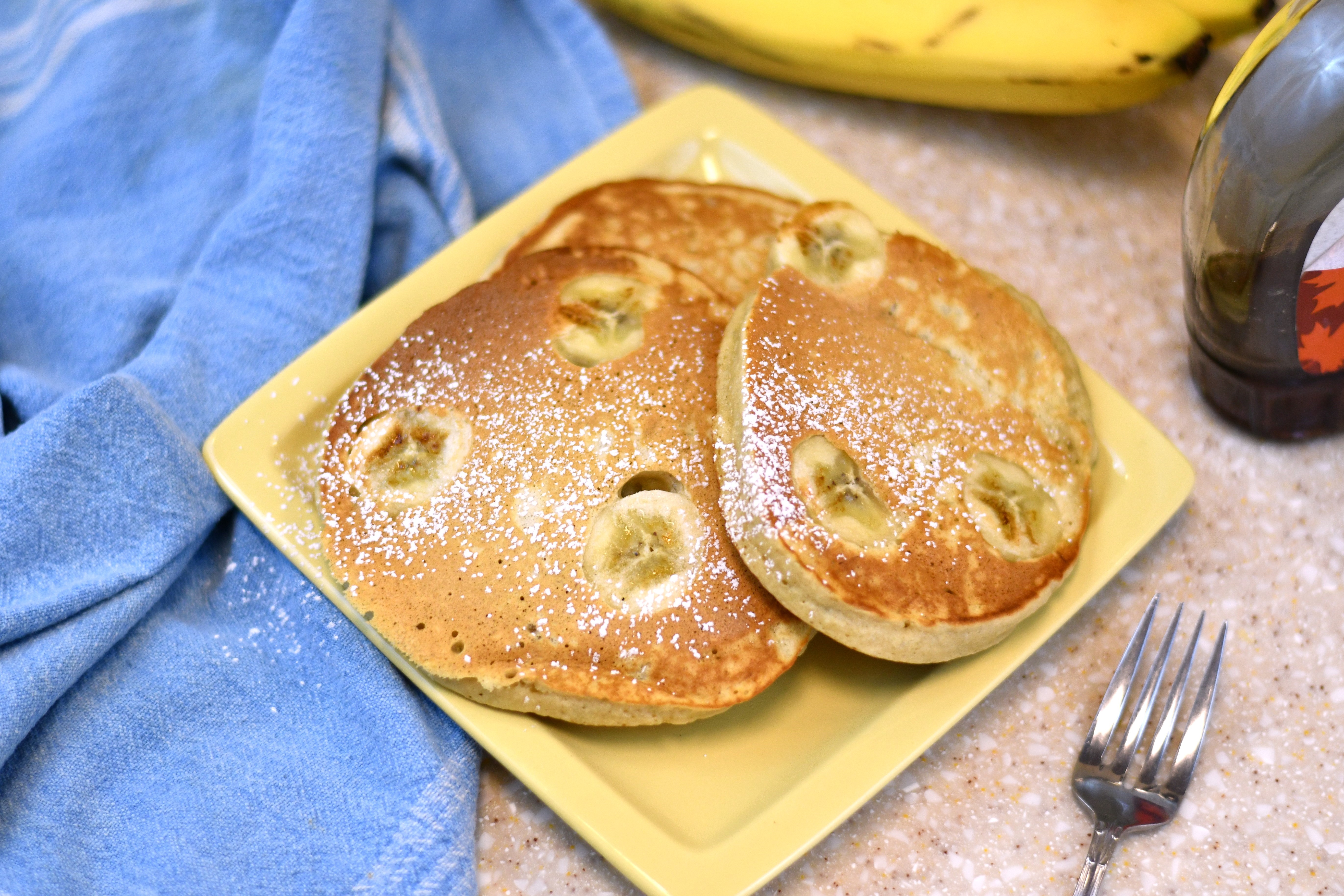 A photo of a plate of pancakes with bananas on them