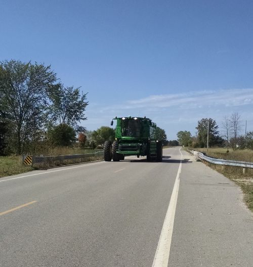 A large green tractor driving down the road.