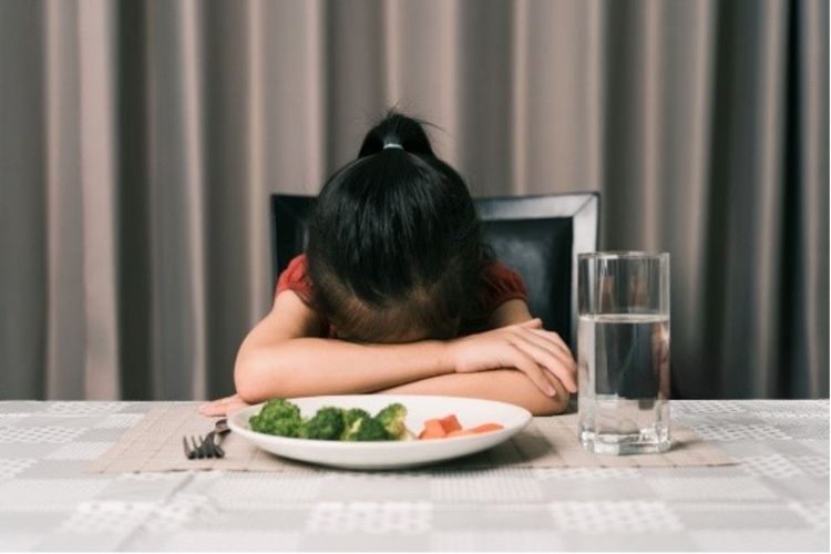 Photo of a child not wanting to eat the food on their plate.