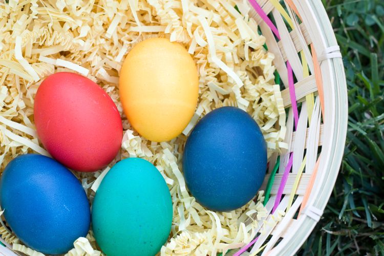 A photo of different colored eggs in a basket.