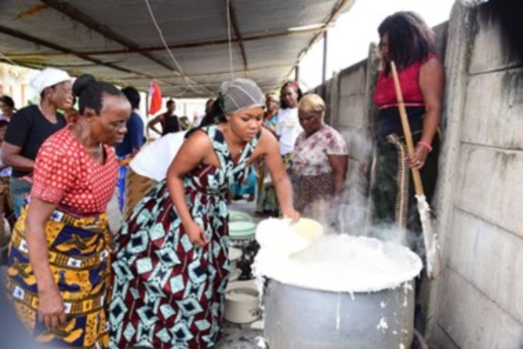 Three women stirring a large pot.