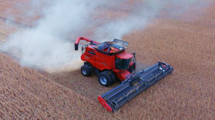 An aerial view of a red harvester harvesting soybeans from a field.