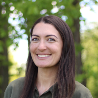 Megan McManus smiles in front of a wooded background