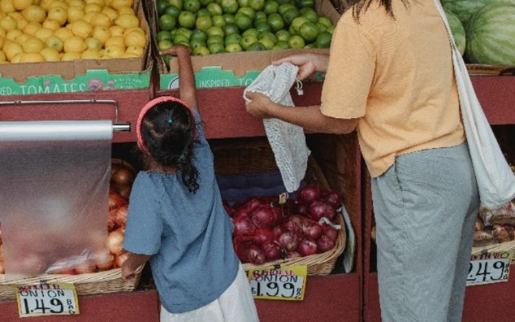 Mom and child picking out fruit at a store.