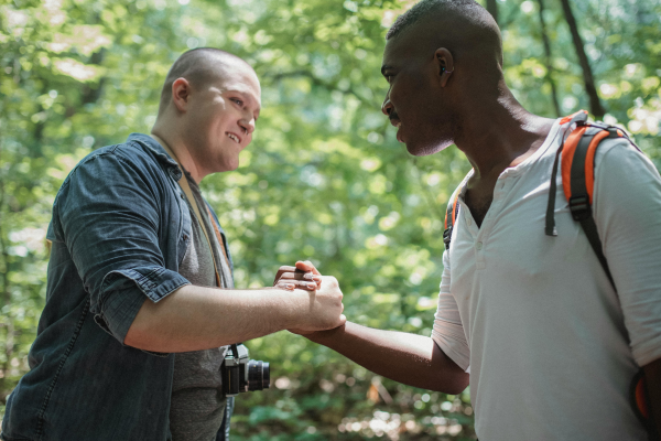 Two men in a forest shaking hands.