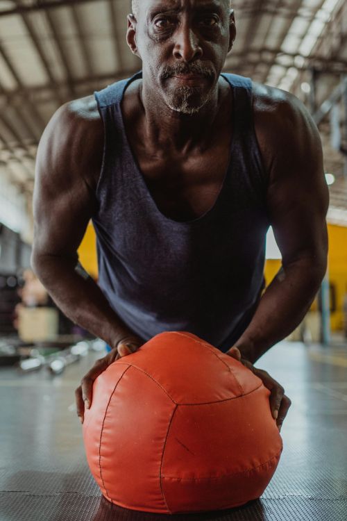 An older man exercising with a medicine ball.