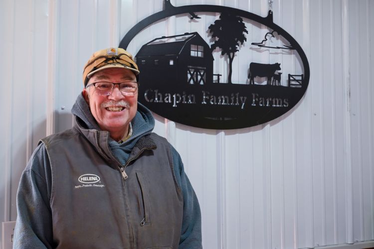 Photo of MMPA Board Chairman Doug Chapin in front of a sign at Chapin Family Farms.