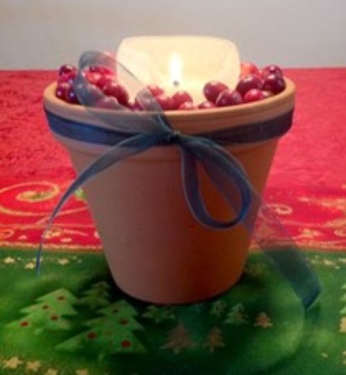 Cranberries and a candle in a terracotta pot.