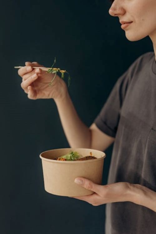A woman eating a bowl of food.