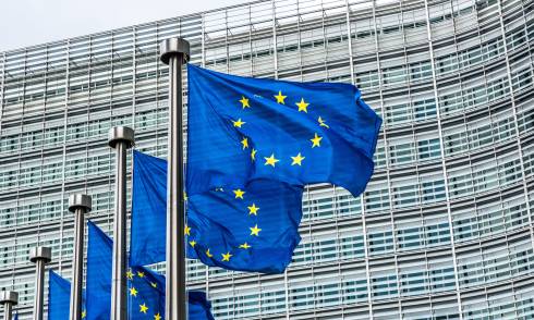 European Union flags flying in front of the EU headquarters building.
