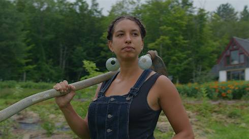 Leah Penniman with a traditional hand-hoe over her shoulder.