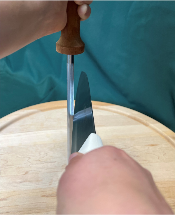 A photo of a knife being sharpened using a honing steel at a 22.5 degree angle.