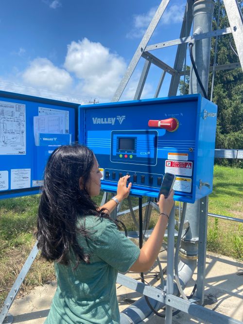 A person programming a blue irrigation box.
