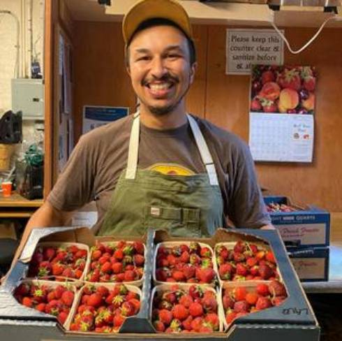Alex Ball smiling with a flat of strawberries.