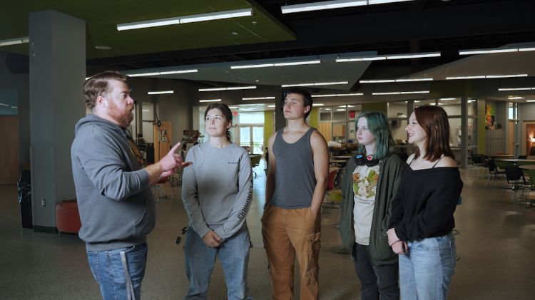A group of students at G2S academy talk with a teacher about upcoming plans for the school food club.
