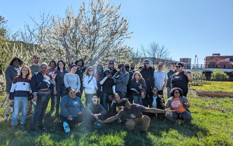A group of past OFTP participants pose together for a picture in front of a tree.