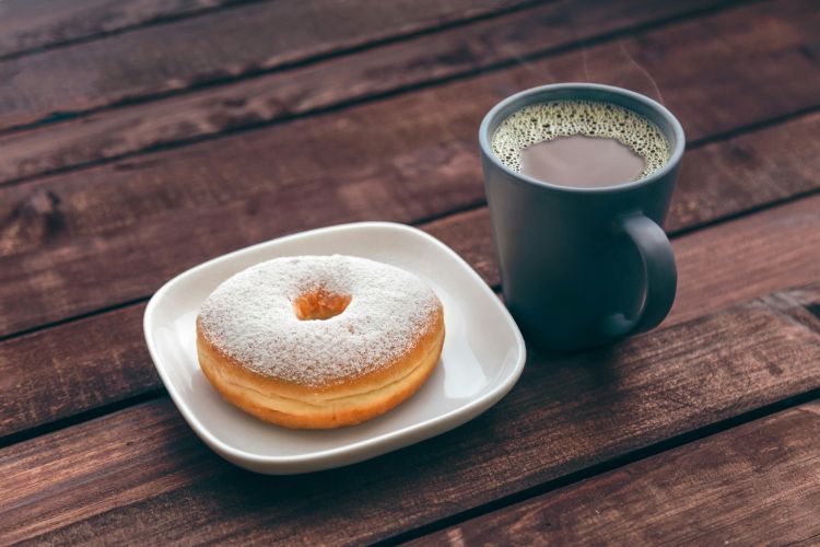 A mug of coffee and a glazed donut.