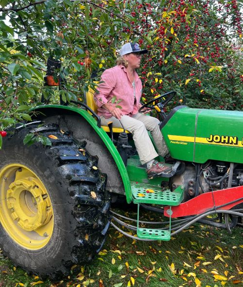 Nikki Rothwell driving a tractor through a cherry orchard.