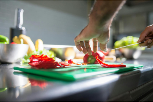 A photo of a person cutting a pepper with a knife.